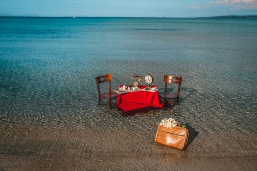 Vintage chairs around a nostalgic table setup on the seashore, featuring a retro aesthetic.