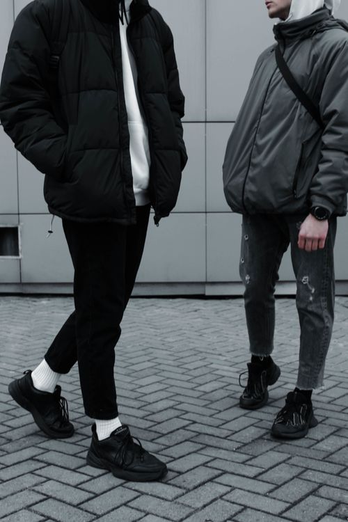 Free Two men dressed in urban streetwear fashion pose against a modern grey wall. Stock Photo