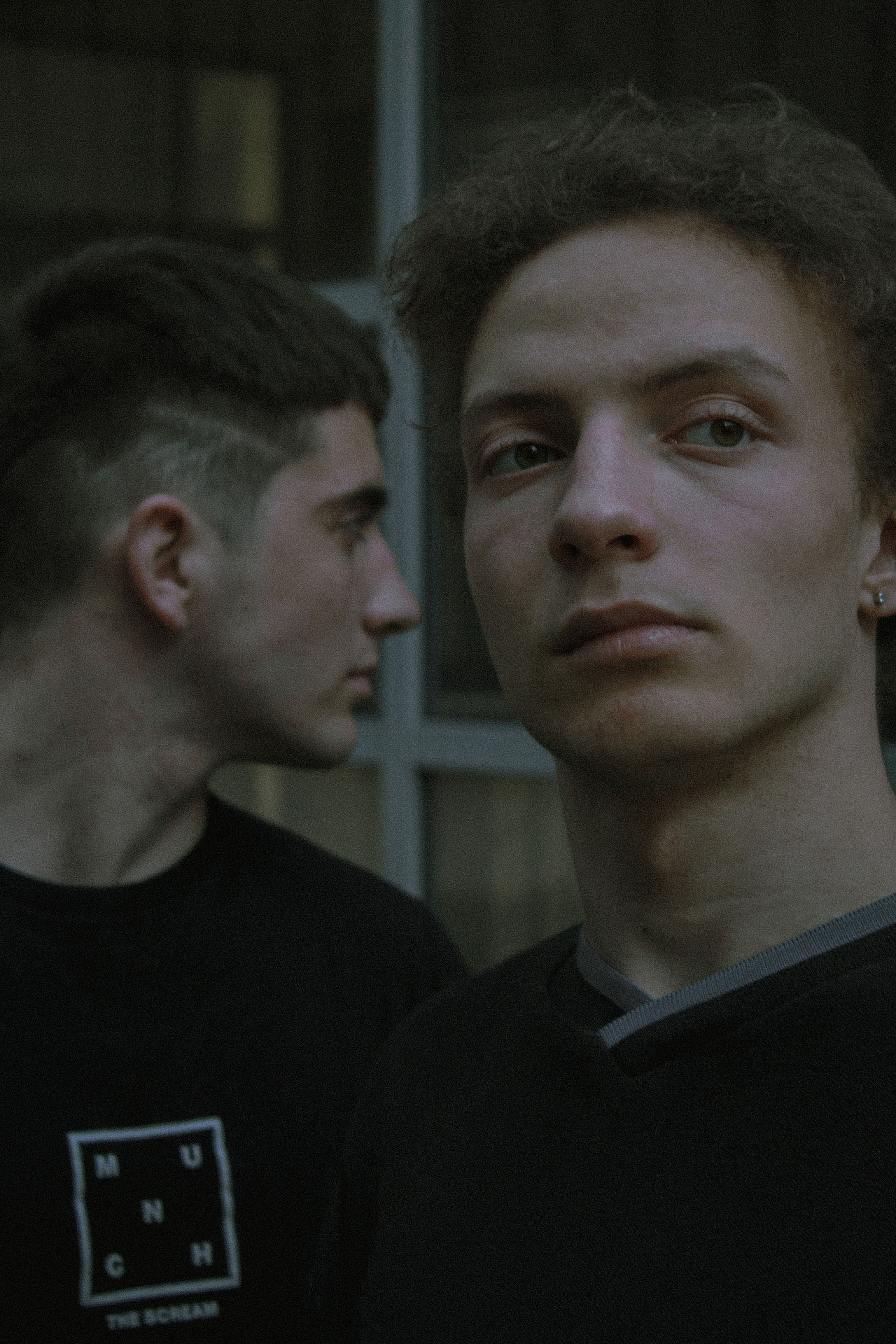 Two young men pose in urban streetwear, reflecting contemporary fashion trends.
