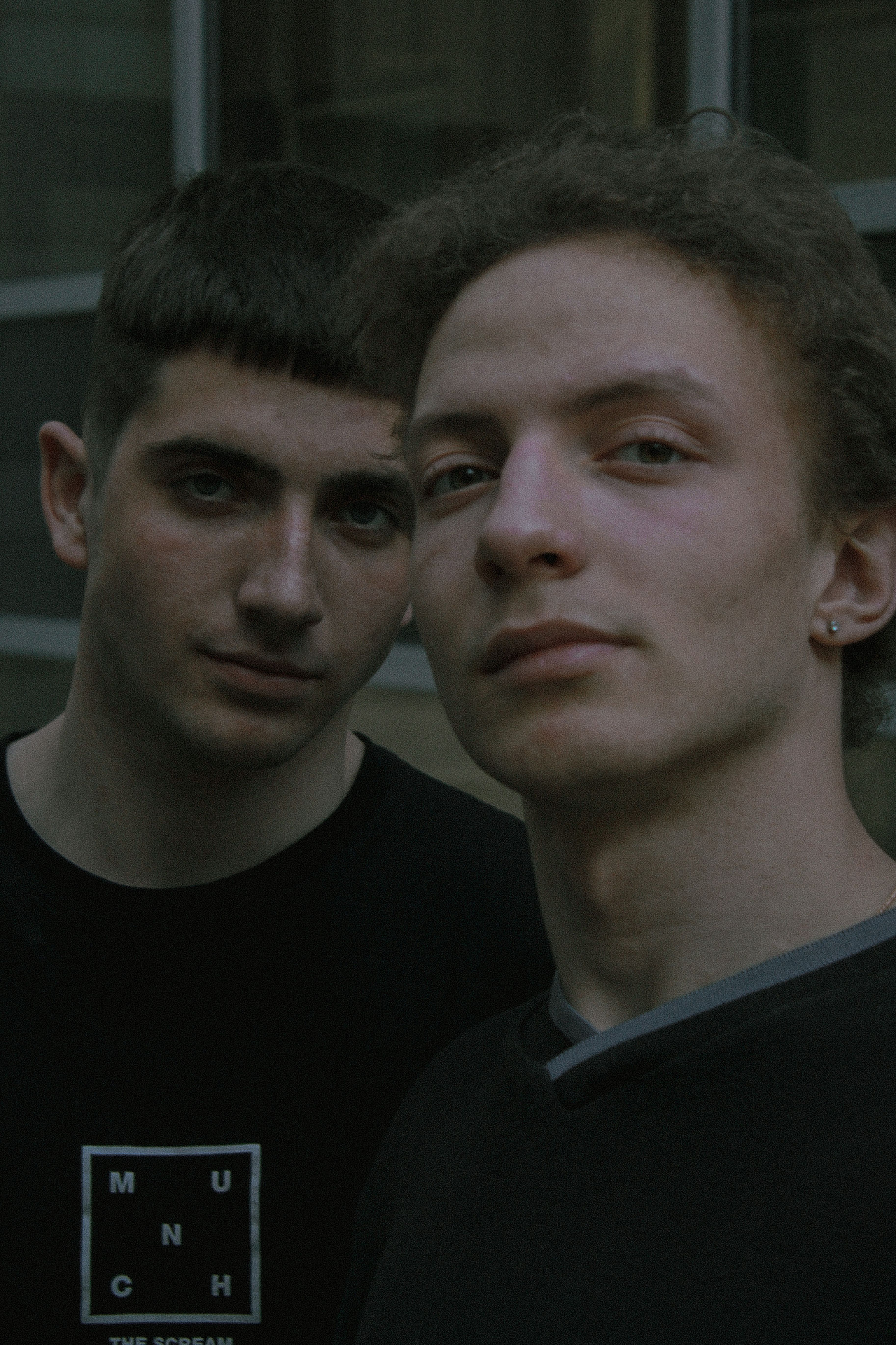 Close-up portrait of two young men with brown and short hair, posing indoors.