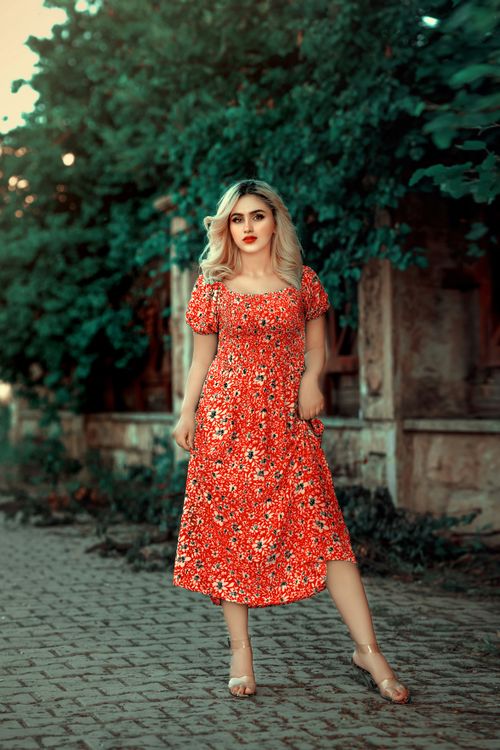Free Stylish woman in a red floral dress poses confidently outdoors in Erbil. Stock Photo