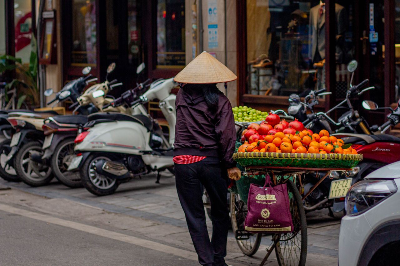a vietnamese street vendor pushes a fruit laden bicycle through the bu