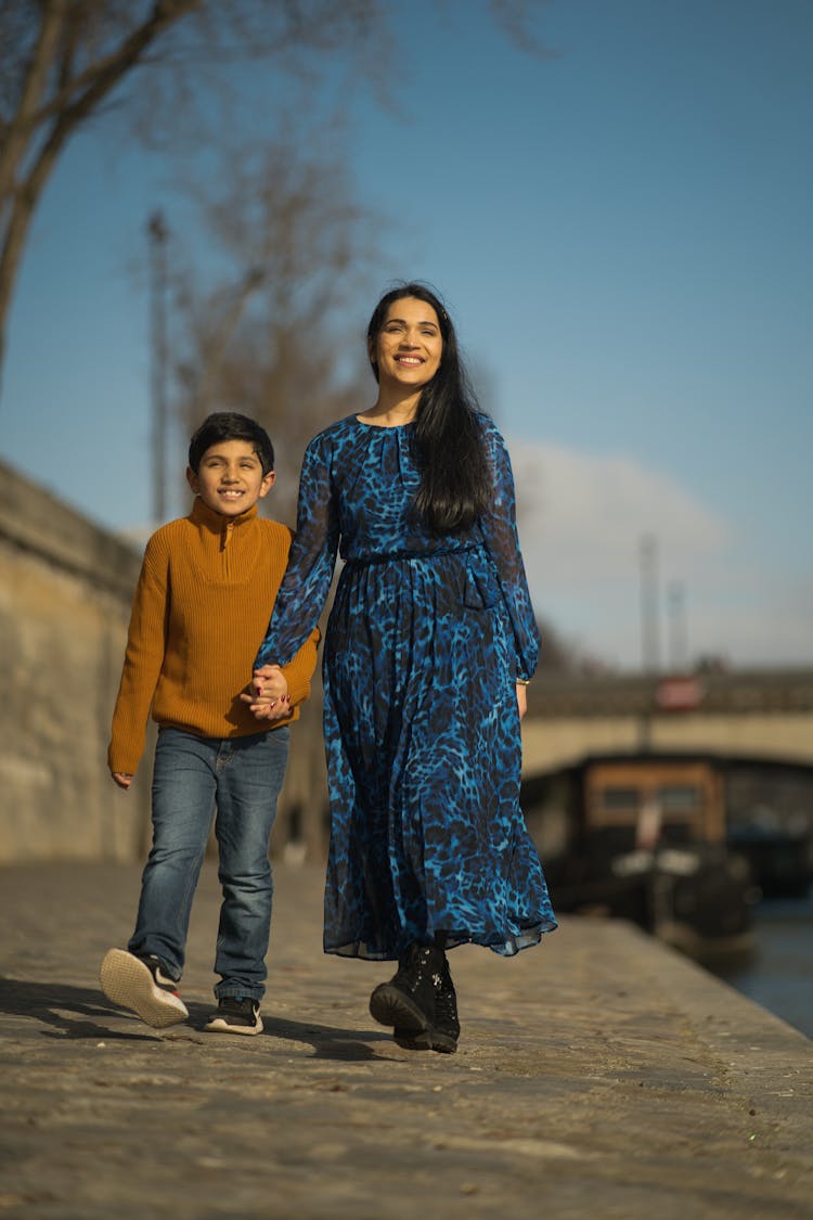 A Woman And Child Walking Along The Waterfront