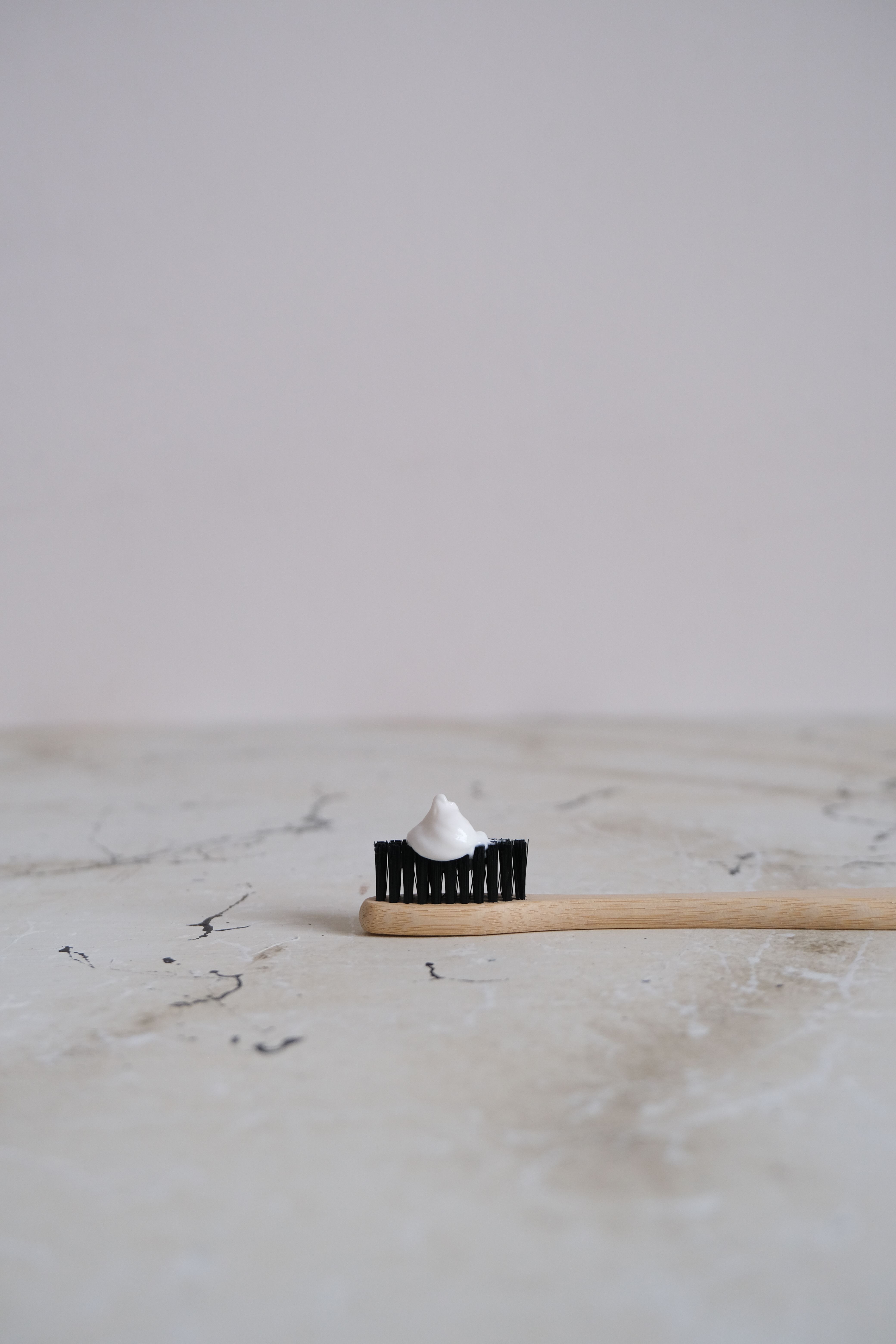 Eco-friendly bamboo toothbrush with toothpaste on a marble background.