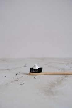 Eco-friendly bamboo toothbrush with toothpaste on a marble background.