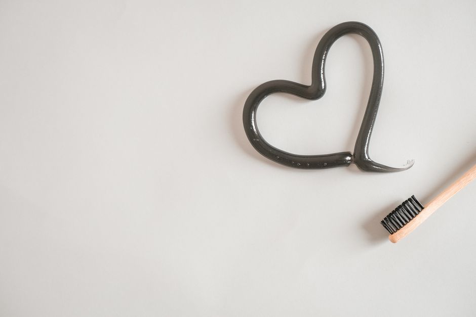 whitening temperature reaction - Heart shape made from charcoal toothpaste with bamboo toothbrush on white background, promoting dental care.