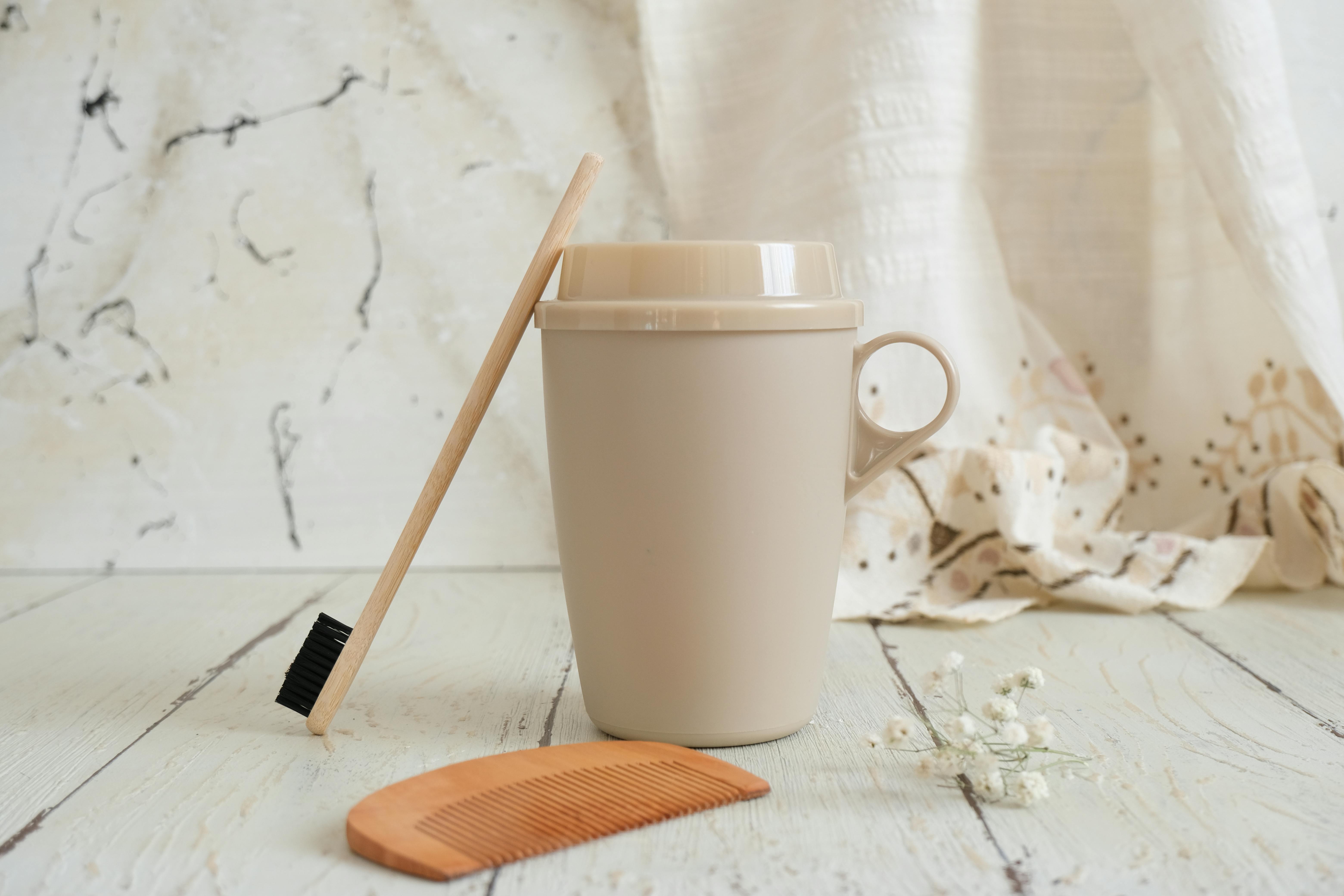 A bamboo toothbrush, ceramic mug, and wooden comb on a rustic surface highlighting eco-friendly living.