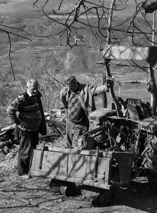Elderly Men Standing by Tractor on Farm