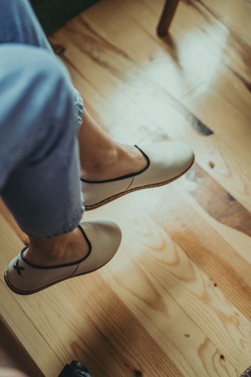Free Close-up of legs wearing casual shoes relaxing on a wooden floor. Stock Photo
