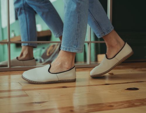 Free Close-up of beige loafers and jeans reflected in a mirror on a wooden floor. Stock Photo