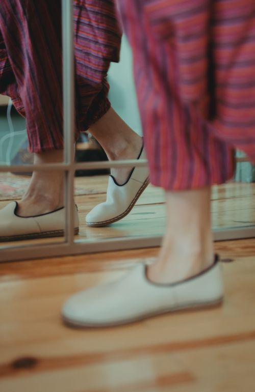 Free A person in striped pajamas and beige shoes captured in a mirror reflection on a wooden floor. Stock Photo