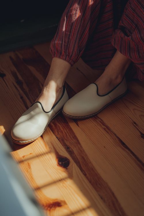 Free Close-up of feet in stylish loafers on a sunlit wooden floor, perfect for casual fashion concepts. Stock Photo