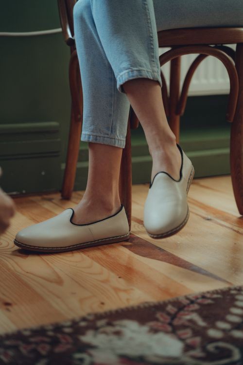 Free Close-up of person wearing beige shoes sitting on a wooden floor indoors. Stock Photo
