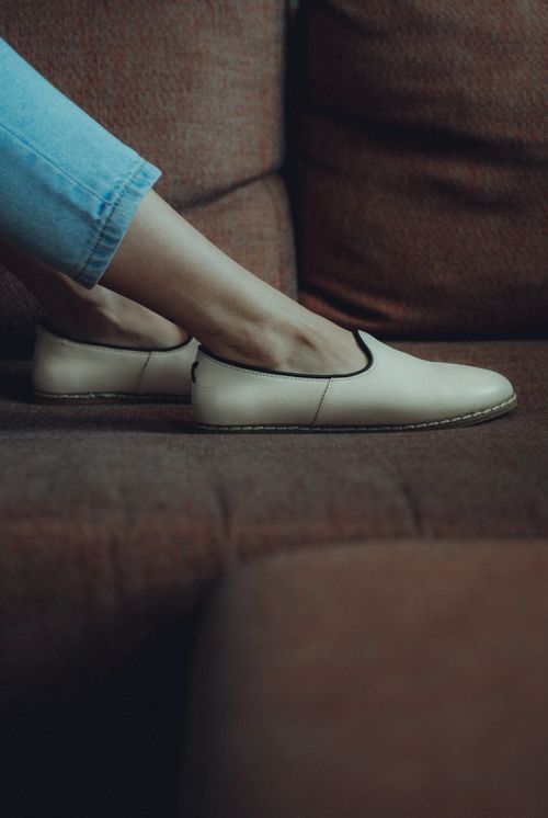Free Close-up shot of stylish beige flats and jeans on a vintage couch, emphasizing casual fashion. Stock Photo