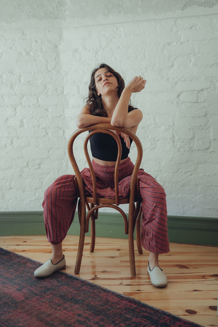 Woman Sitting Backwards On Wooden Chair