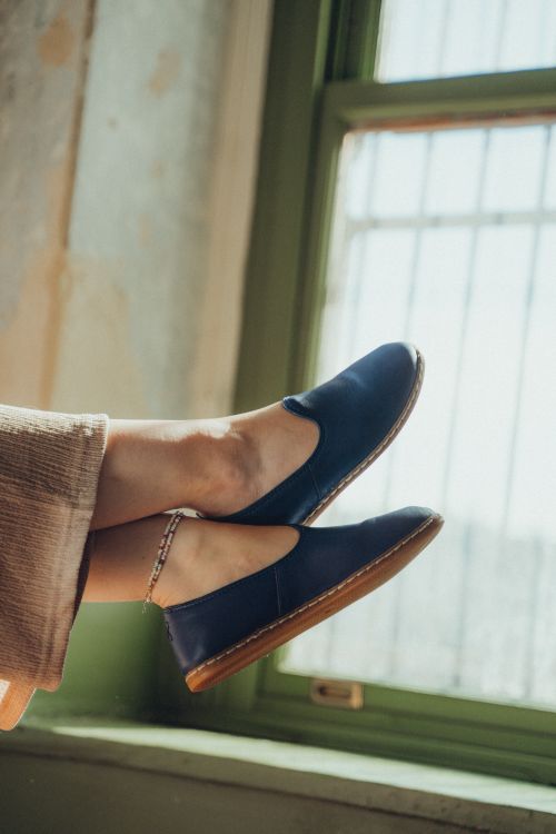 Free Close-up of legs wearing blue loafers by a window, showcasing casual fashion. Stock Photo