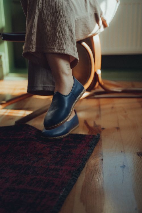 Free A close-up of a woman's legs wearing stylish footwear indoors, highlighting fashion and comfort. Stock Photo