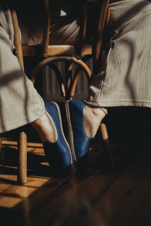 Free Close-up of a person in stylish attire with blue shoes sitting on a chair. Stock Photo