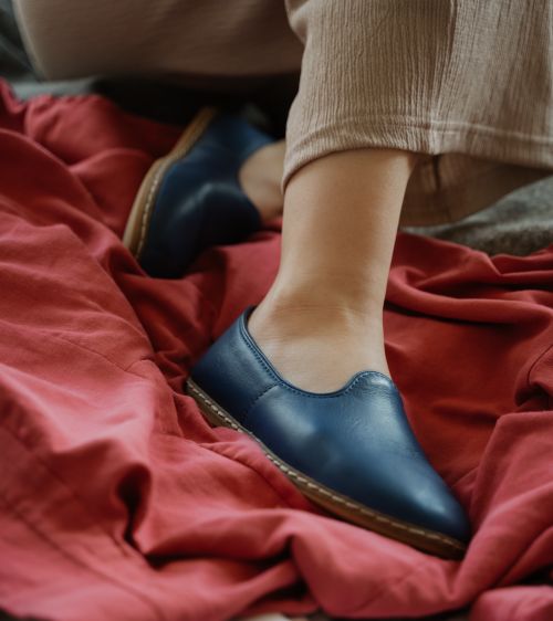 Free Close-up of a woman's legs wearing blue shoes on red fabric, captured indoors. Stock Photo