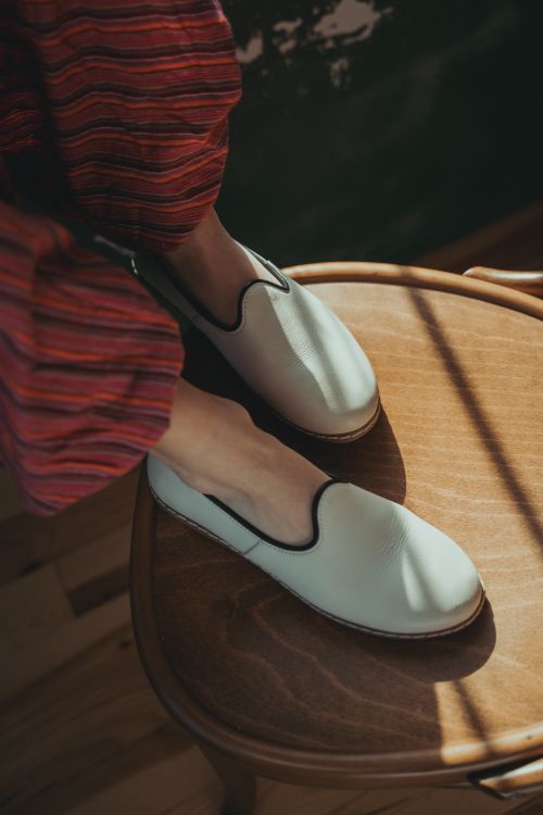 Free Cozy slip-on shoes with red striped pants and wooden chair in warm lighting. Stock Photo