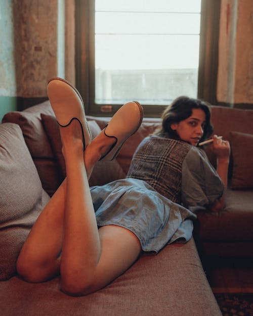 Woman Lying on Sofa with a Pen in her Hand 