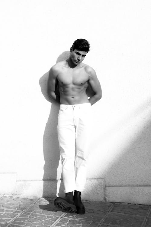 Shirtless Model in White Pants Standing on the Sidewalk