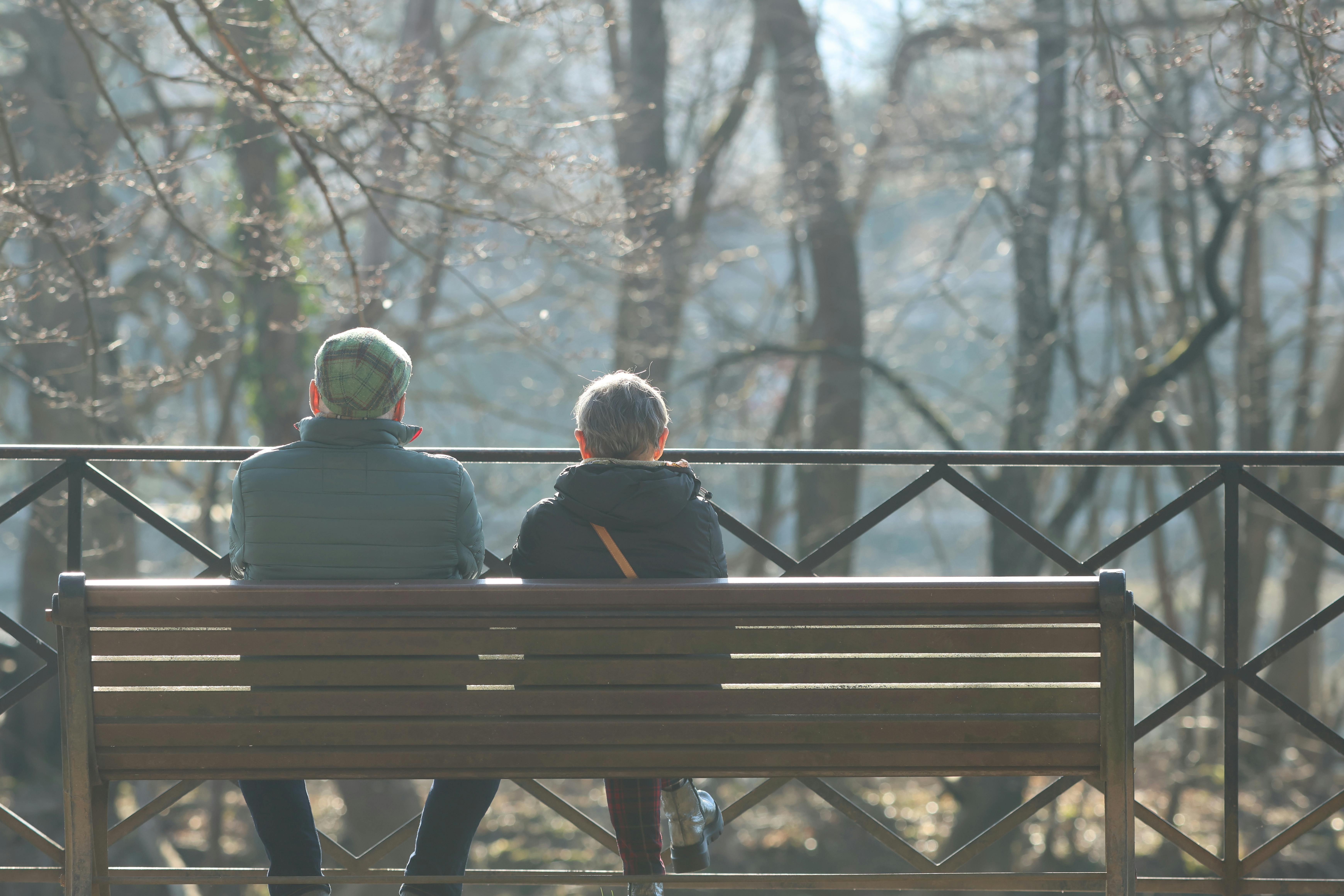 Senior couple enjoys a peaceful moment on a bench during a sunny autumn day in the park.