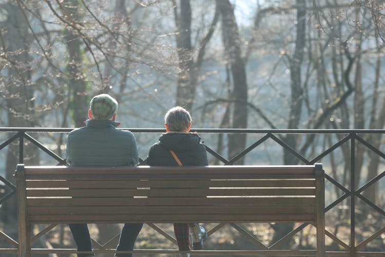 Old Couple Sitting On Bench In Park