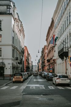 Streets of Budapest with classic architecture, cars, and sunlight.