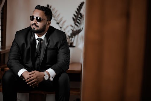 Handsome Man in Sunglasses and Suit Sitting Indoors