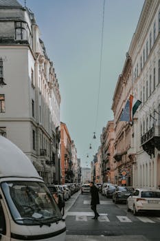 Historic street scene in Budapest with cars, buildings, and a pedestrian crossing in daylight.