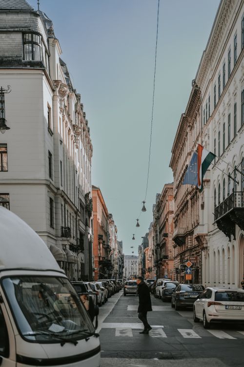 Free Historic street scene in Budapest with cars, buildings, and a pedestrian crossing in daylight. Stock Photo