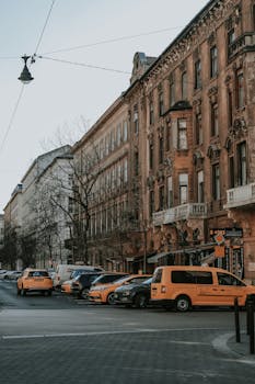 Vintage buildings on a Budapest street with parked yellow taxis, capturing urban and historical vibes.