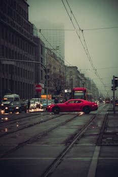 A red car on a rainy street in Warsaw, capturing urban life.
