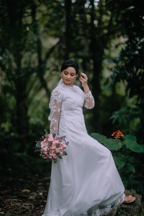 Woman Posing in Wedding Dress among Trees