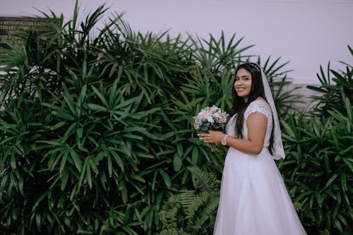 Brunette Woman in Wedding Dress Standing near Bush