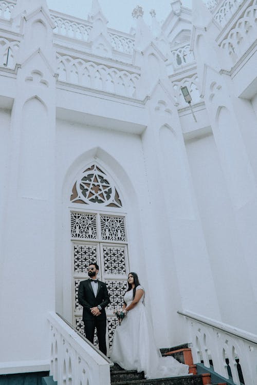 Newlyweds Posing by Ornamented Building White Walls