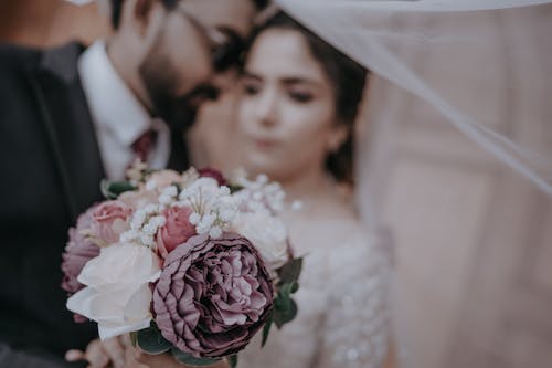 Close-up of a Wedding Bouquet and a Newlywed Couple Standing in the Background 