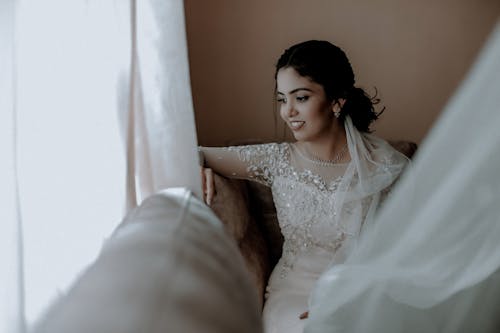 Beautiful Bride Sitting on the Sofa and Looking out the Window 