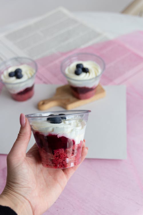 Woman Hand Holding Homemade Yogurt Dessert in Plastic Cup