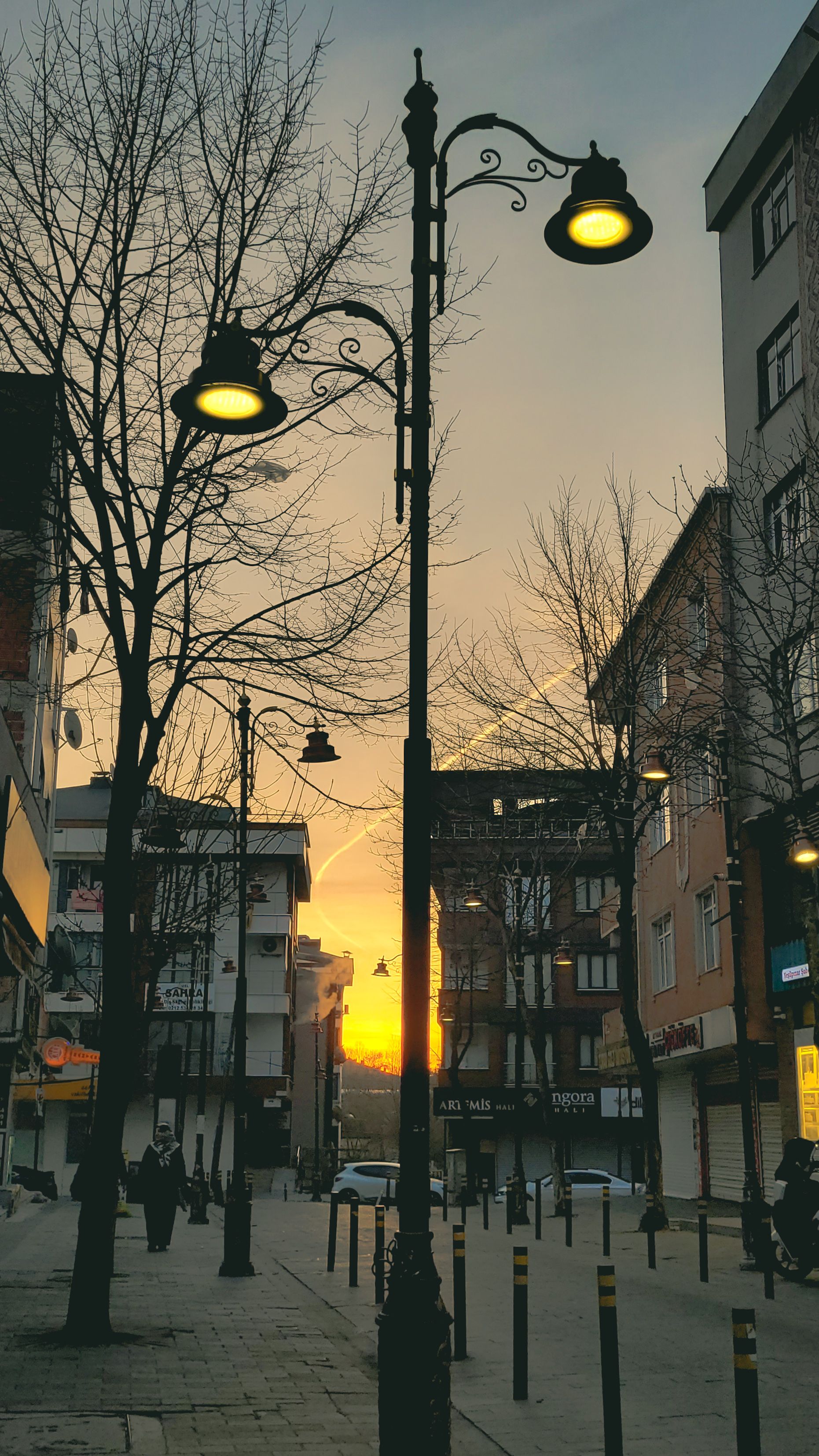 Scenic urban street view at dusk with illuminated streetlights and townhouses.
