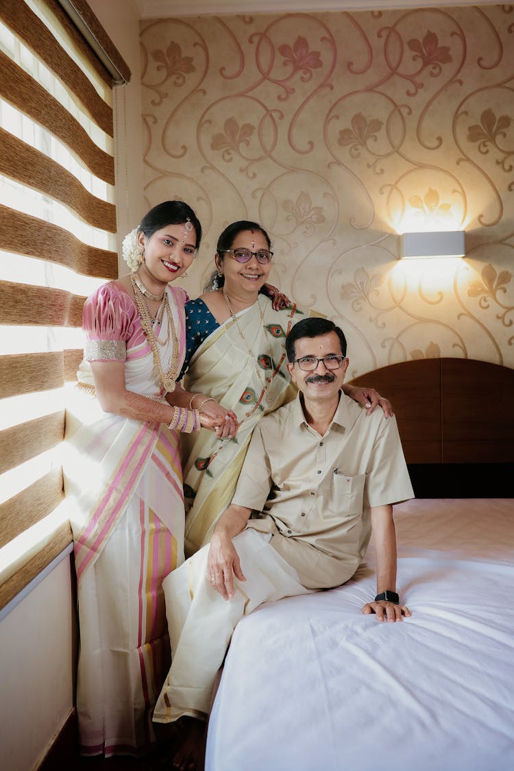 Family In Traditional Indian Clothing Posing In A Hotel Bedroom 