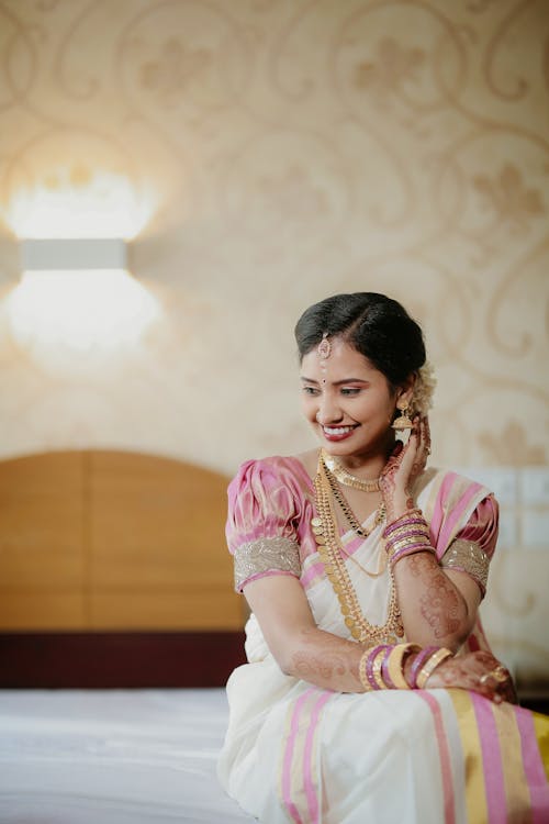 Smiling Young Woman in Sari Sitting on a Bed