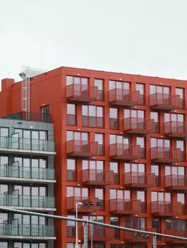 Contemporary urban architecture featuring a striking red facade and balconies.