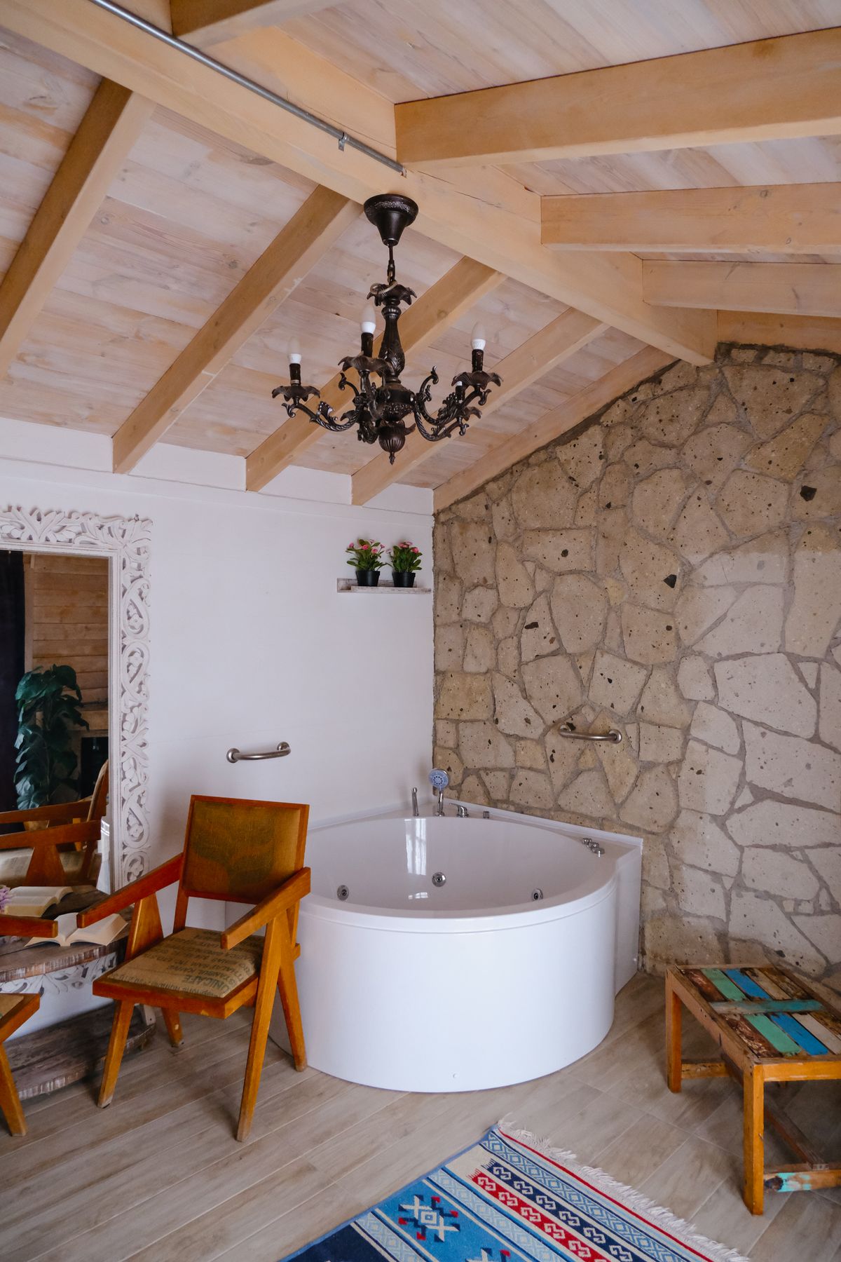 Cozy rustic bathroom design featuring a round bathtub and stone wall with vintage decor. Stock Photo.