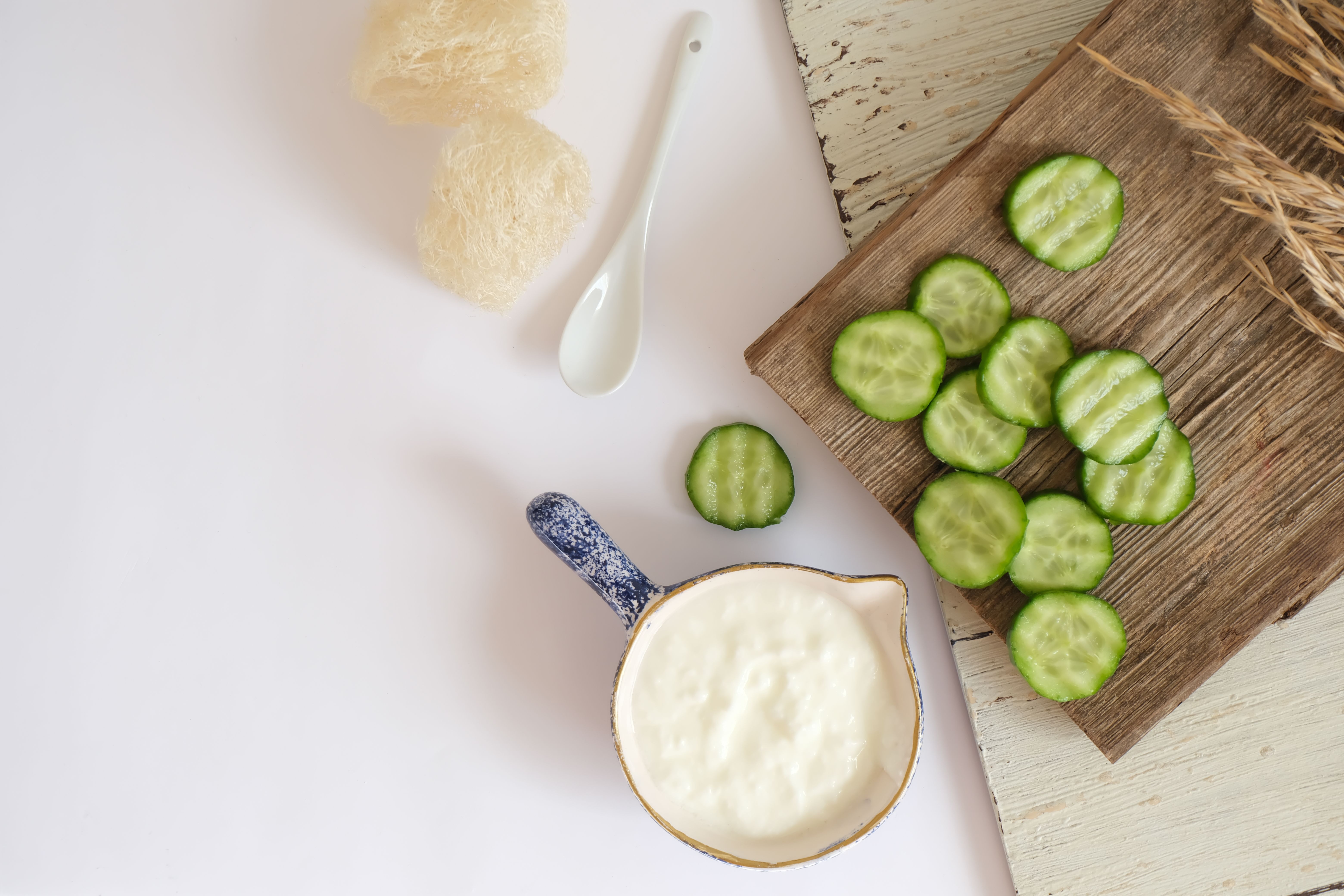 Flat lay of cream in a jug with cucumbers on a wooden board. Perfect for healthy eating themes.