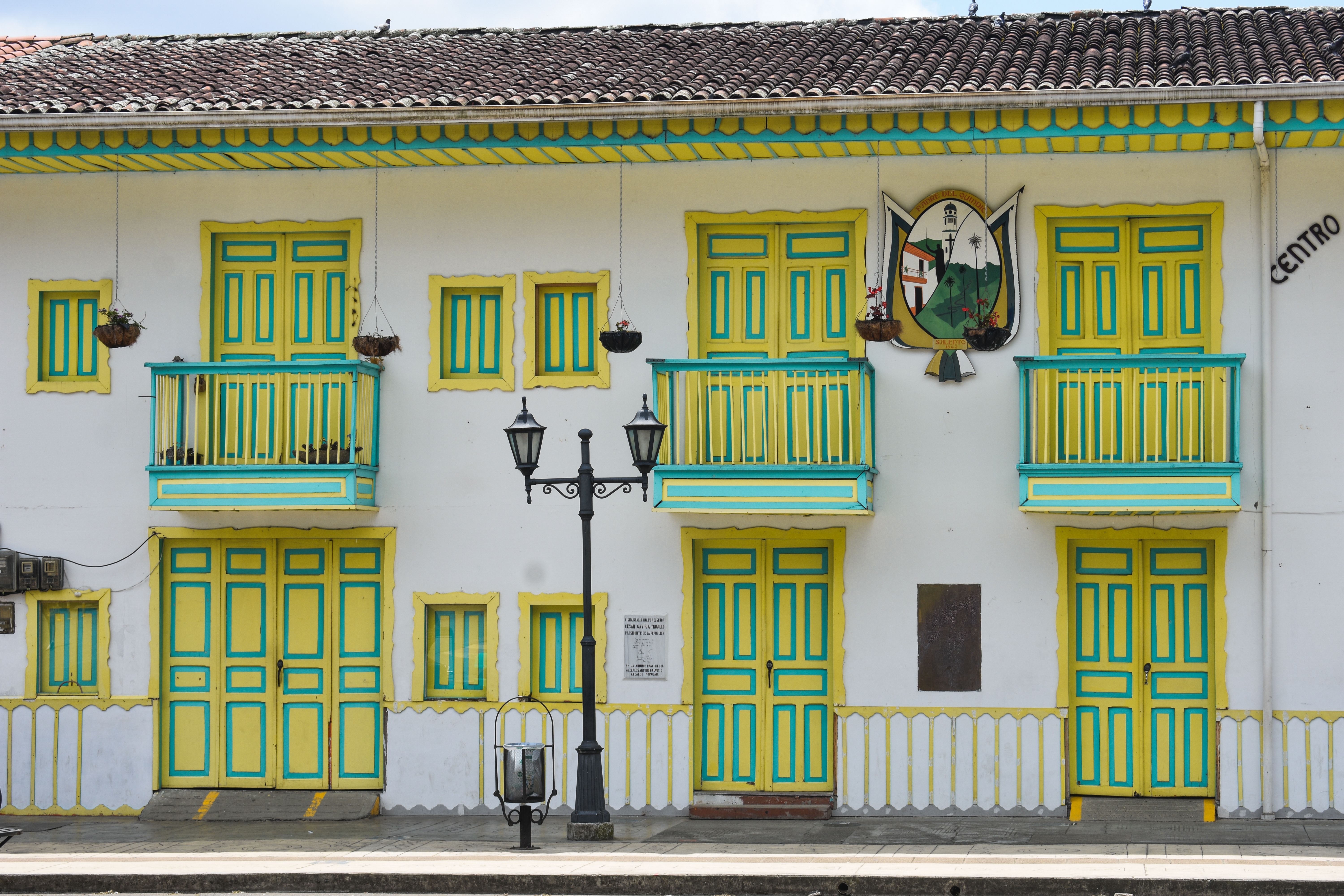 Brightly painted colonial building facade with yellow and green doors and windows in a lively street setting.