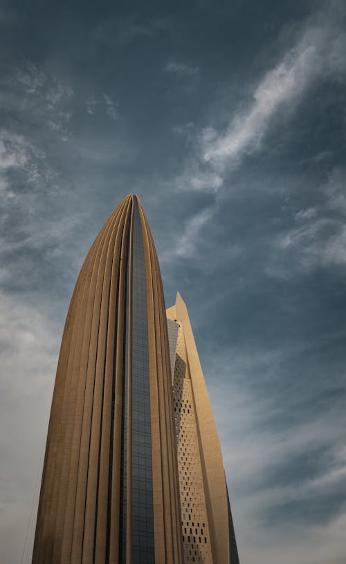 A tall building with a large window and a cloudy sky