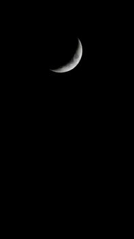 A striking crescent moon photographed against a dark sky, offering ample copy space.