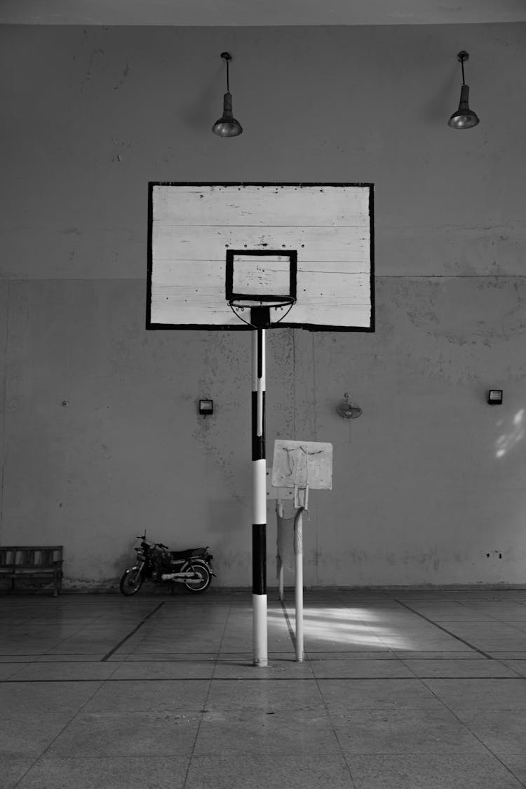 A Black And White Picture Of A Basketball Hoop In A Gymnasium 